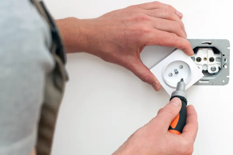 Électricien posant une prise de courant murale