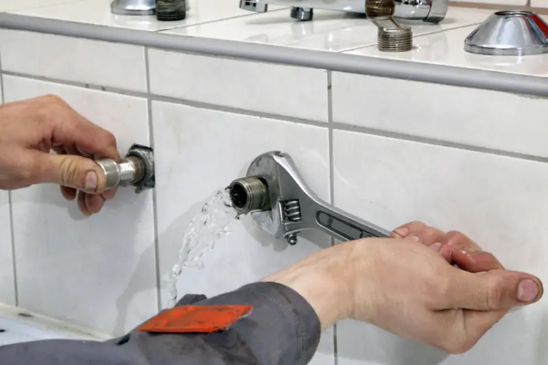 Plombier resserrant un raccord de robinetterie à la clé à molette