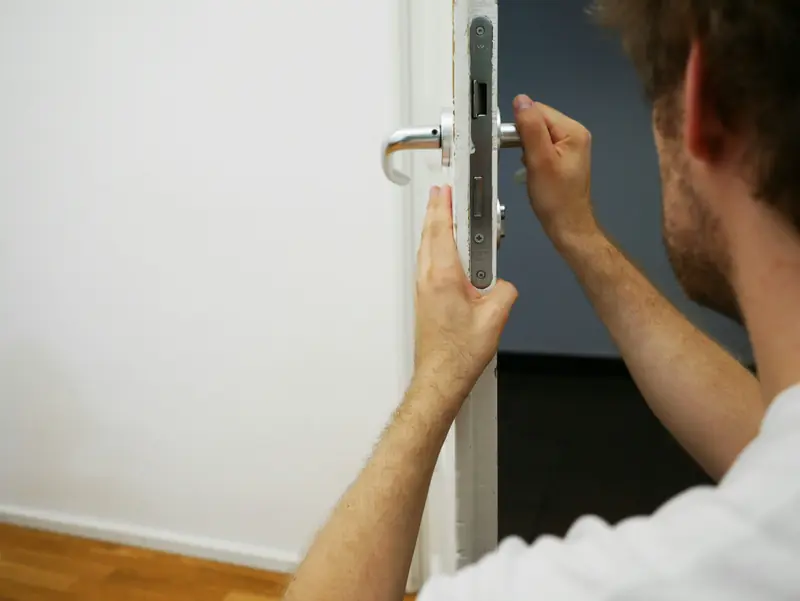 Artisan intervenant sur la serrure d'une porte